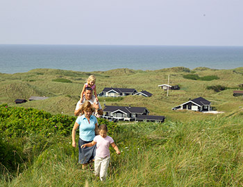 Eine Familie auf dem Grundstück ihres Ferienhauses mit Aussicht zum Meer