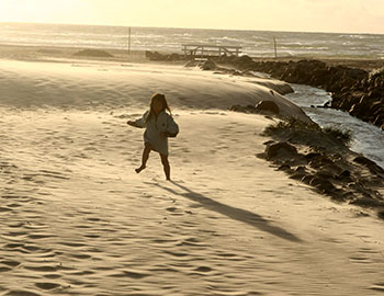Ein kleines Mädchen läuft am Strand von Lökken