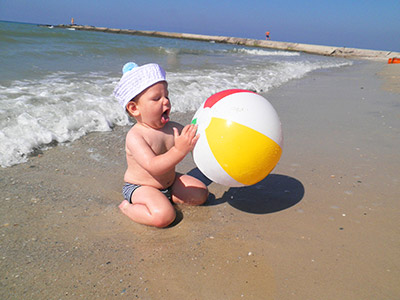 Kleiner Junge an der Wasserkante mit großem Wasserball