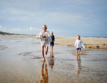 Drei frohe Kinder spielen am Strand